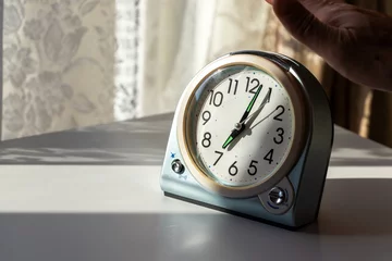 Fotobehang 窓際の机に置かれた目覚まし時計のアラームを留める © 木村　亨