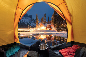 View from inside a tent of tourist relaxing and looking to the wooden lodge glowing on Emerald Lake...