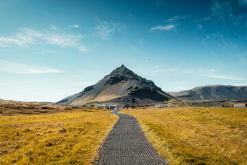 Stapafell volcanic mountain in Arnarstapi fishing village and pathway through golden meadow at...
