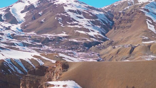 Chicham village as seen from the Chicham bridge near Kibber in Spiti Valley, Himachal Pradesh, India. Village under the snow covered mountain divided by a fault line in the mountain in India. 