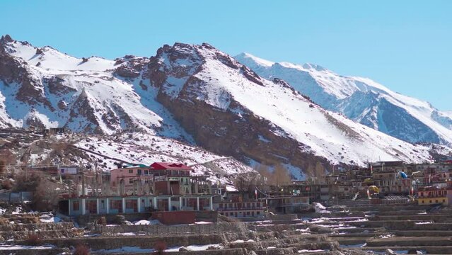 Nako Village in front of snow covered Himalayan mountain peaks as seen on the way to Spiti Valley in Himachal Pradesh, India. Beautiful mountain village in the Himalayas in winter season in India.