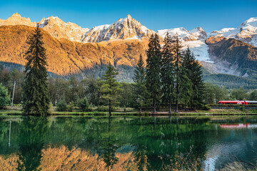 Lac des Gaillands with train passing and Mont Blanc massif reflection in the sunset at Chamonix,...