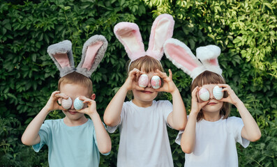 Smiling children wearing a headband with bunny ears found Easter eggs in the garden and brought...