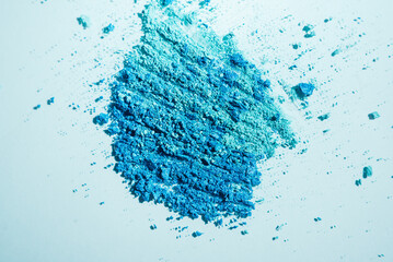 Close-up of texture of broken blue eyeshadow on a blue background. Cosmetics texture