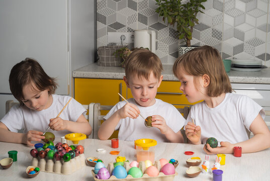 Children in the kitchen paint eggs. Preparing for Happy Easter. Religious holiday traditions concept
