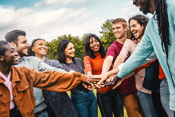 A multiethnic group of friends displays teamwork and unity, showcasing diversity and collaboration in a natural outdoor setting. - obrazy, fototapety, plakaty