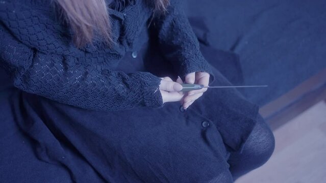 Girl is thinking with a knife in her hand on the bed whether to hurt herself or not. The difficult period of adolescence associated with self-harm in adolescents leads to loneliness and lack of care