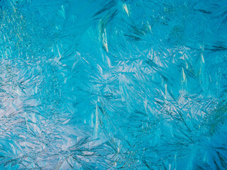 Beautiful ice pattern and sunlight close up on window glass early in the morning, natural winter background  