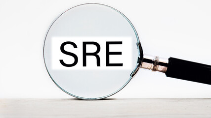 SRE. Site Reliability Engineering lettering on through a magnifying glass on a light background - obrazy, fototapety, plakaty