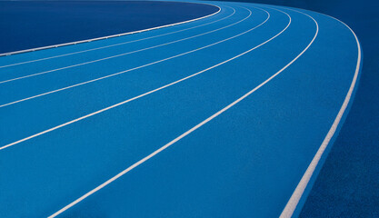 Blue Olympic track lanes with white stripes, an empty background suitable for copy space, represent the concept of physical sports and running, symbolizing commitment and pathways towards goals