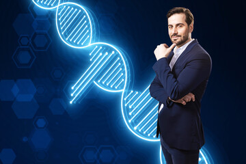 Thoughtful young european businessman with folded arms and glowing DNA helix on blurry blue...