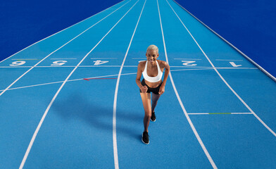 An African American female athlete is running on the Olympic blue track, embodying the concept of...