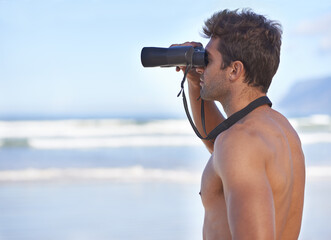 Man, binoculars and lifeguard on beach in search or checking danger for health and safety. Face of...
