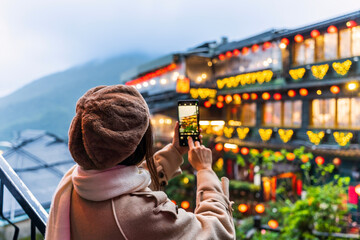 Naklejka premium Young female tourist taking a photo of Jiufen old street landmark and popular attractions in Taiwan