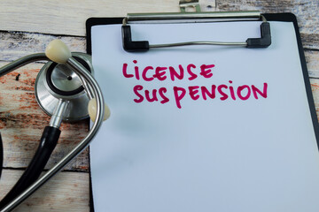 Concept of License Suspension write on paperwork with stethoscope isolated on wooden background.