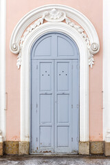 Arched closed gray wooden door in pink wall, background texture