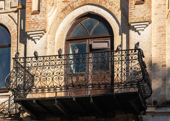 Pigeons sit on railing of wrought-iron balcony of ancient building built in mid-19th century....