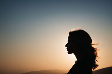 Silhouette of a woman against the sunset backdrop