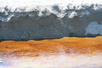 Stained stream flowing through sand 