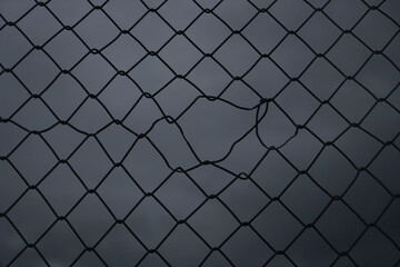 black silhouette of Steel mesh fence with torn hall in it. damage wire mesh over white background....