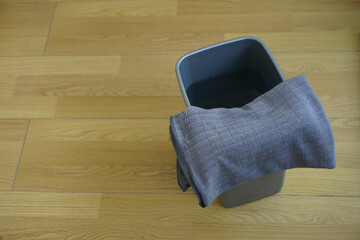 Floor wooden parquet and grey rag, plastic basket with pure water. empty copy space for inscription. top view. day light.