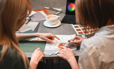 Close up hand choosing color from color sample swatch. The designer works with the customer and...