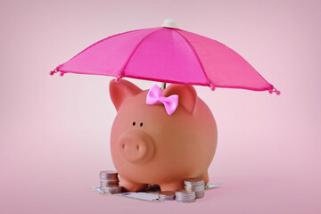 Piggy bank with hair bow and money under pink umbrella - Concept of woman, savings and and financial security - 723663220