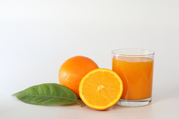glass of orange juice and oranges on white background