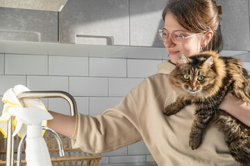 A young woman kills the kitchen with her pet cat. Cleaning an apartment with pets