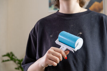 A large amount of cat hair on clothes. Cleaning clothes with a special roller. Horizontal photo