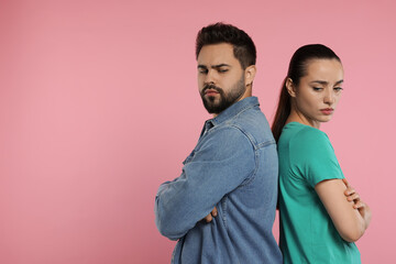 Resentful couple with crossed arms on pink background, space for text