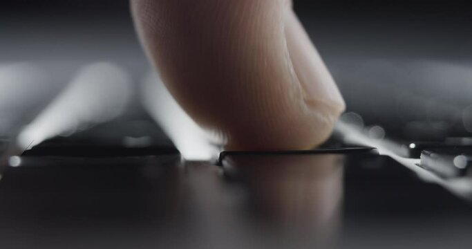 Extreme Close-up of Finger Pressing Keys on Laptop Keyboard