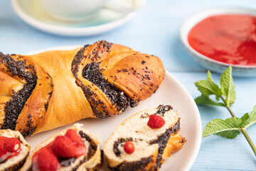 Sweet bun with strawberry jam on a blue wooden background, side view, selective focus.