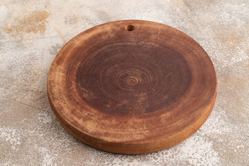 Empty round wooden cutting board on brown concrete. Side view