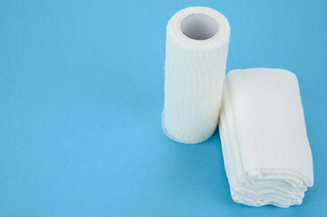 Self-fixing cohesive bandage and gauze sterile wipes, on a blue background.