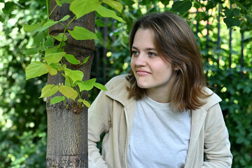 Young woman gloating and watching someone from behind a tree, close up