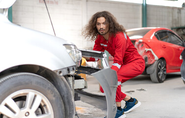 Auto mechanic repairman working on transport body bumper assembly on damaged car at motor repair...