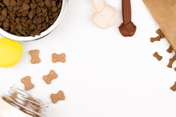 Top view of things for dogs: a metal bowl with dry food, treats for dogs, bones, tennis ball. Life with dog concept. Dog food concept.