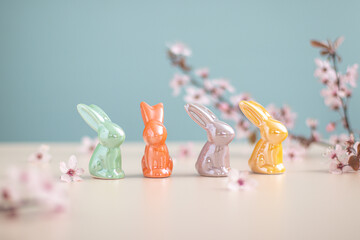 An arrangement of multicolored ceramic Easter bunny figurines with cherry blossoms on a pastel...