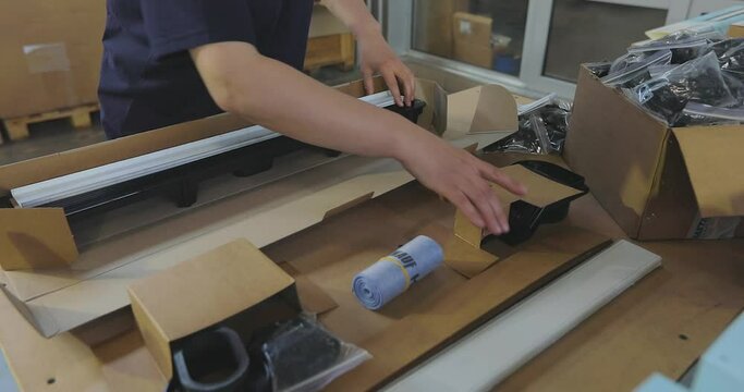 Packer work in a factory. A woman packer packs a product into a box. Packing the goods in a box.