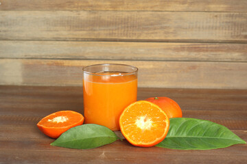 tangerine juice in a glass and tangerines on wood 