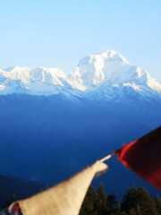 A breathtaking panorama of majestic mountains stretching far and wide, accentuated by a vibrant red flag in the forefront.