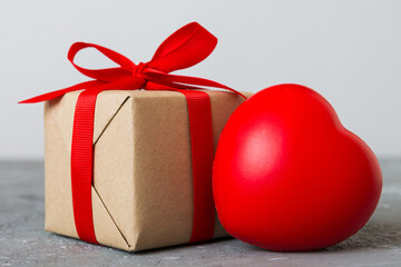 gift box with red bow and red heart on colored background. Perspective view. Flat lay