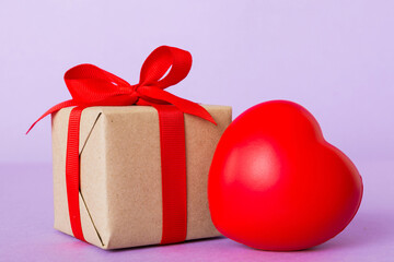 gift box with red bow and red heart on colored background. Perspective view. Flat lay
