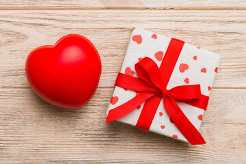 gift box with red bow and red heart on colored background . Top view. Flat lay