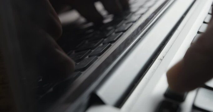 Laptop Screen Reflecting Image of Fingers Typing on Keyboard