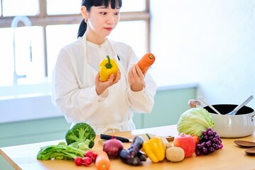 キッチンで野菜を手に取る若い女性