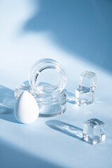 Close up photo with beauty products for your skin , blender , creme  in glass , ice cubes on blue background