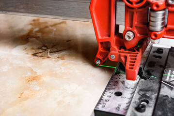 Close up of cutting ceramic tile with red manual tile cutter.