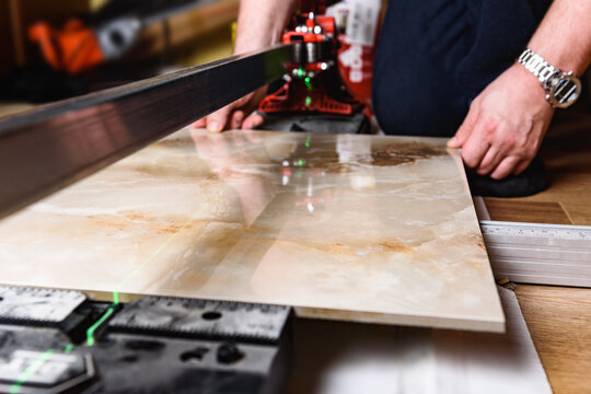 Man cutting ceramic tile with manual tile cutter.